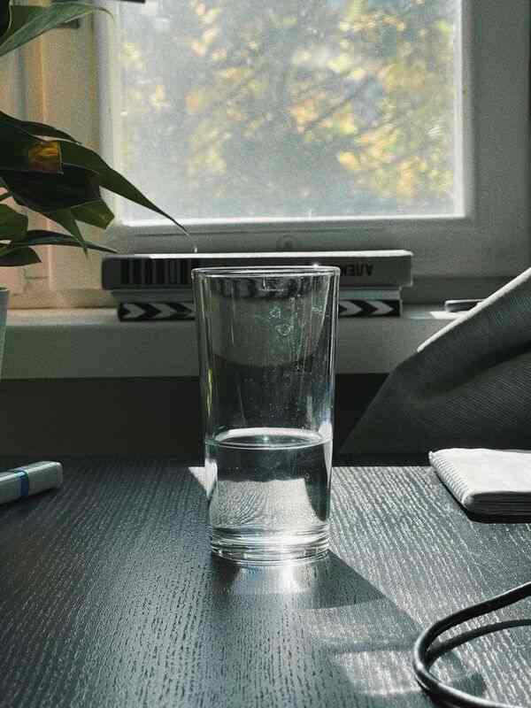 Vaso de agua sobre una mesa con luz natural, ambiente tranquilo