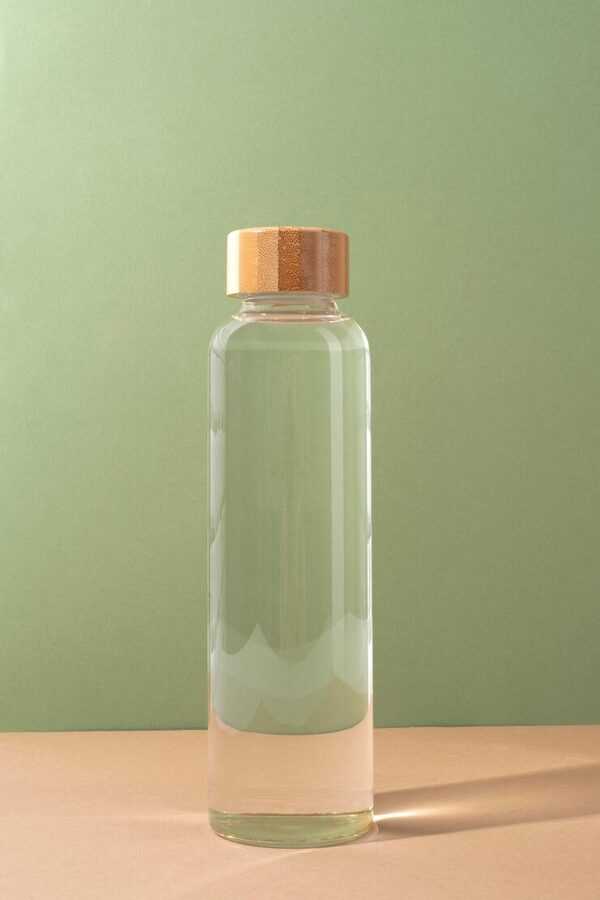 Botella de agua sobre una superficie clara con luz suave